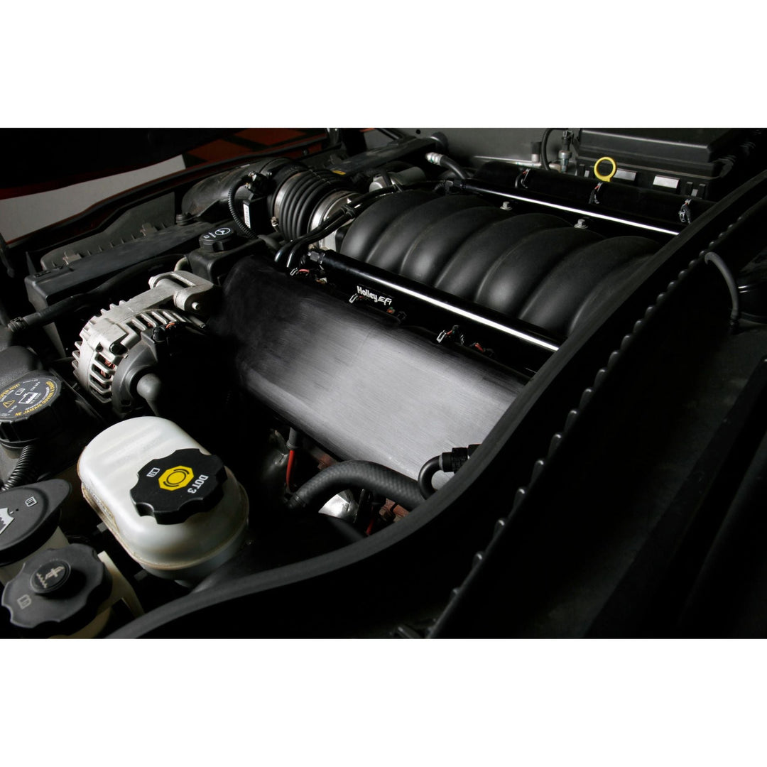 A close-up view of a car engine featuring billet fuel rails for factory LS intake and other engine components.