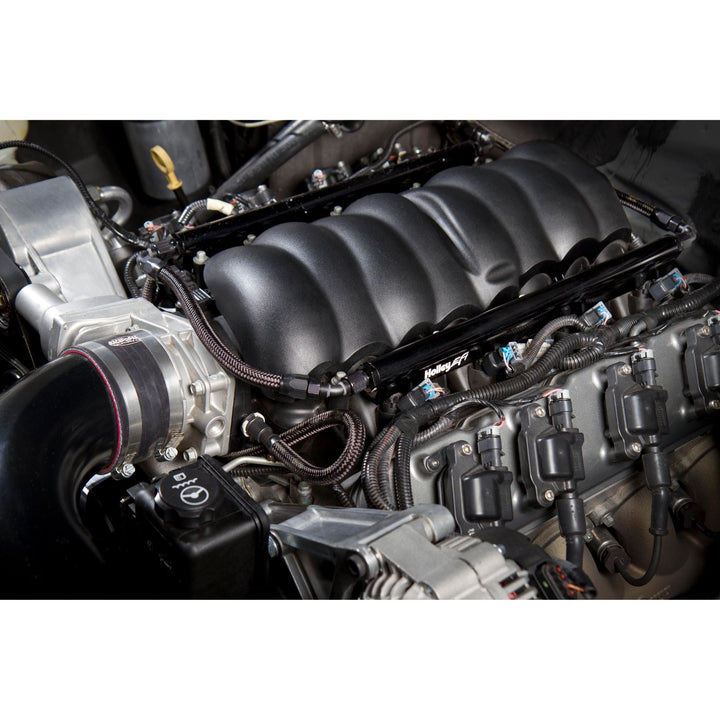A close-up view of a car engine Holley EFI fuel rail kit for LS engine and other mechanical components.