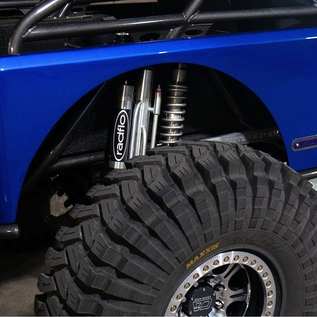 Close-up of a blue vehicle with a tire and suspension system, featuring Radflo 4 tube bypass shock absorber.