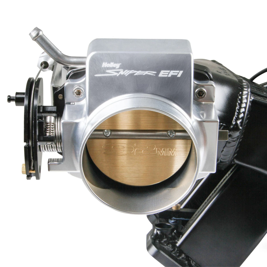 A close-up of a Holley Super EFI 92mm throttle body assembly with a silver aluminum body, a brass butterfly valve, and black components, shown against a white background.