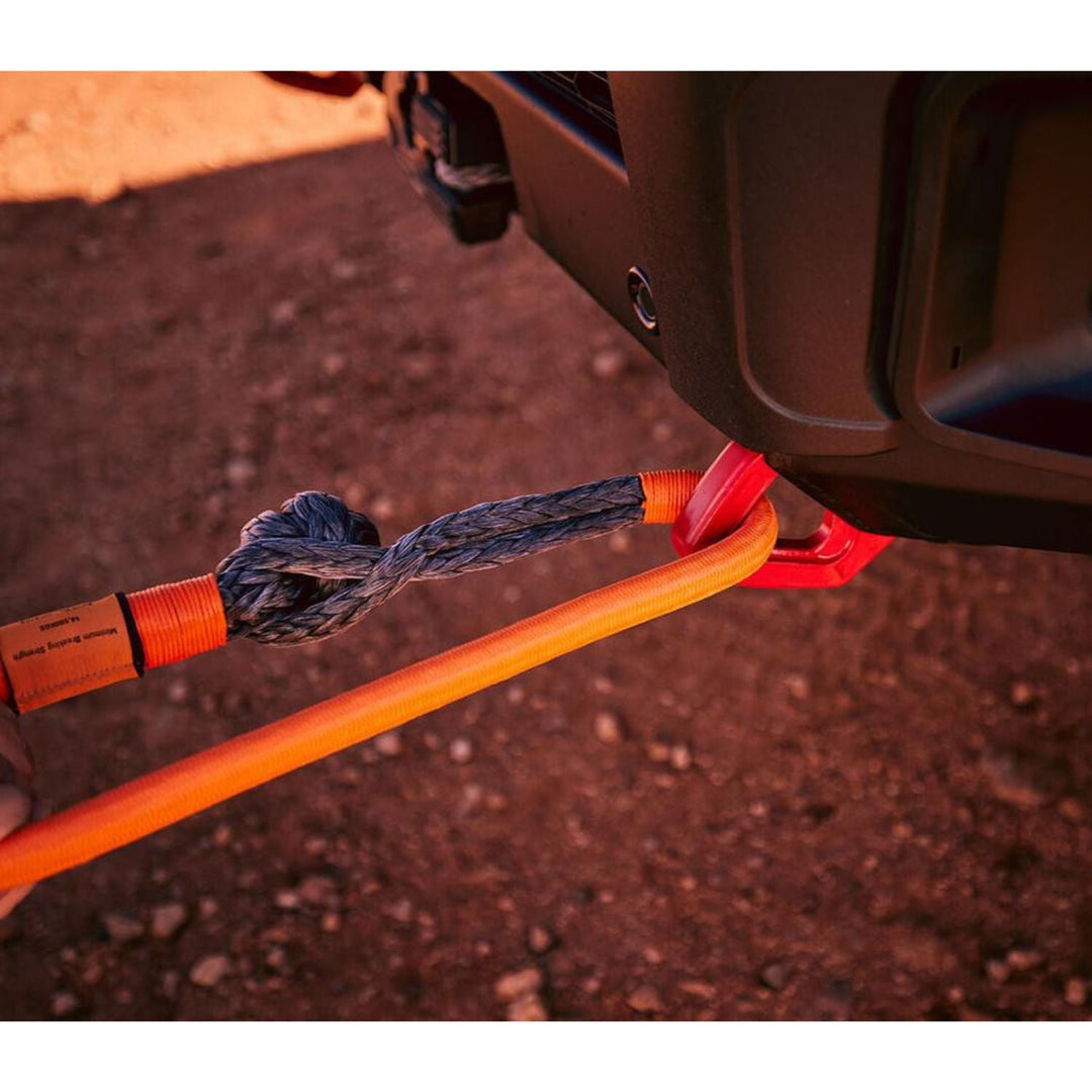 Orange Off-road soft shackle safer than steel attached to a vehicle on a dirt road