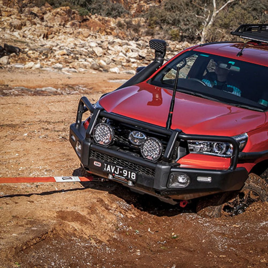Red off-road vehicle on a rocky terrain using a Heavy duty snatch strap for 4x4